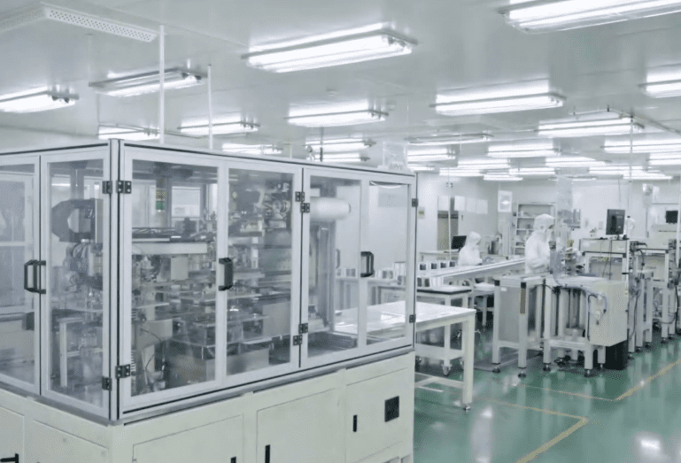 A technician in a cleanroom outfit working in a semiconductor manufacturing facility.